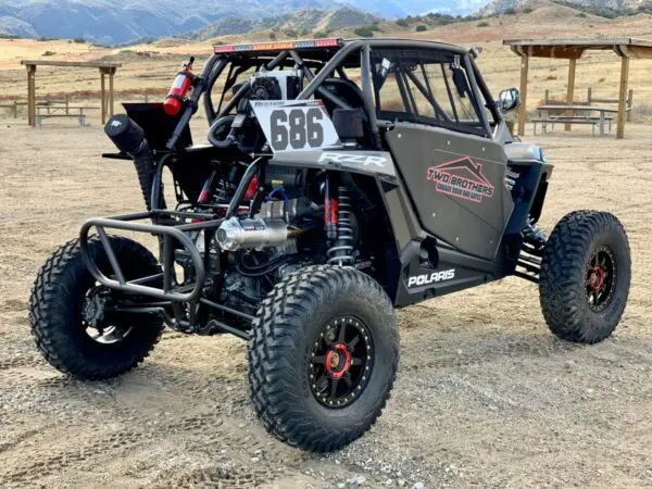 A black and silver buggy parked in the dirt.