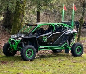 A green and black four-wheeled vehicle parked in the woods.